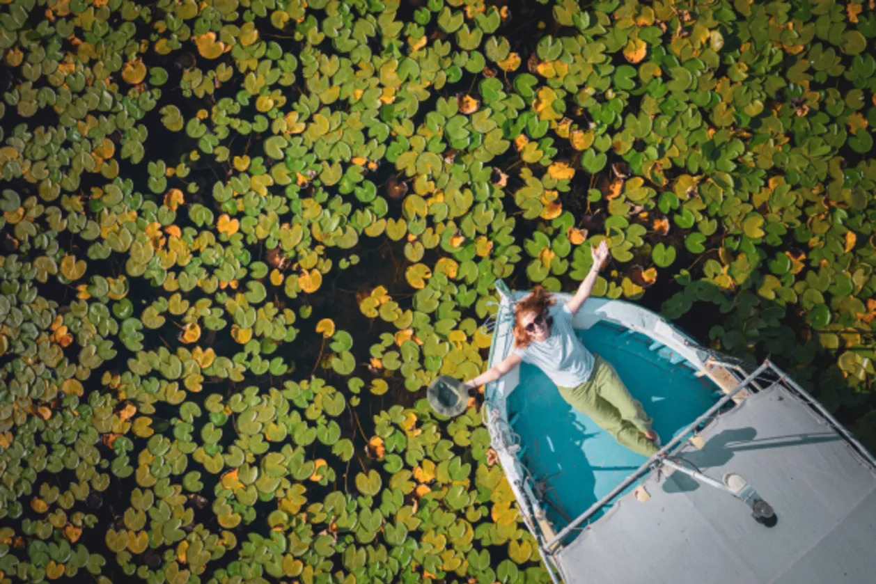 aerial view of woman on wellness getaway in lotus water lily lake